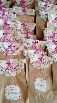 brown paper bags with pink bows and doily on them are lined up in rows