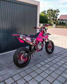 a pink dirt bike parked in front of a garage