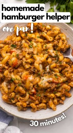 a white bowl filled with pasta covered in meat and cheese, on top of a table