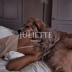 a woman laying on top of a bed next to a dog