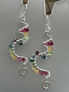 These gorgeous sterling earrings laden in colorful gemstones are reminiscent of vines, new birth, awakening, and longing for spring! The sterling frames are hand shaped in a unique abstract swirling pattern, and hammered for a shimmery texture. Gemstones wrapped in sterling wire add more sparkle to these frames. Finished with sterling ear wires and components.  Gemstones include: Spinel Sapphire Kyanite Tanzanite  Peridot Topaz Citrine Excellent gift idea for that free spirited friend or family Silver Fusion Style Wire Wrapped Earrings, Whimsical Sterling Silver Dangle Earrings, Whimsical Sterling Silver Drop Earrings, Whimsical Sterling Silver Jewelry With Matching Earrings, Whimsical Multicolor Sterling Silver Jewelry, Whimsical Multicolor Wire Wrapped Jewelry, Multicolor Wire Wrapped Sterling Silver Earrings, Artsy Multicolor Sterling Silver Jewelry, Artsy Sterling Silver Multicolor Jewelry