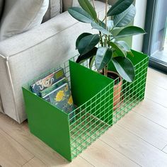 two green bins with magazines in them sitting on the floor next to a couch