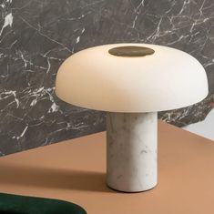 a white lamp sitting on top of a table next to a black and brown wall