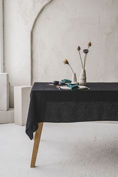 two vases with flowers sit on a table in front of a white brick wall