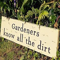 a sign that says gardeners know all the dirt in front of some bushes and plants