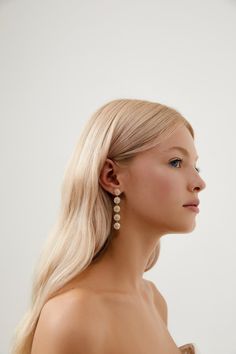 a woman with long blonde hair and earrings on her head looking off to the side