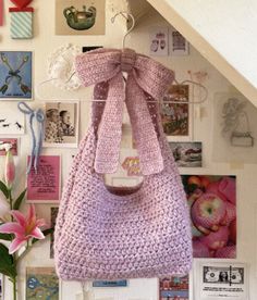 a crocheted purse hanging on a wall with pictures and flowers in the background