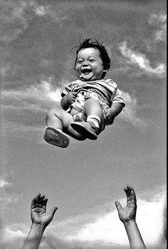 a black and white photo of two hands holding a baby in the air