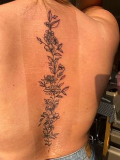 a woman's back tattoo with flowers on it