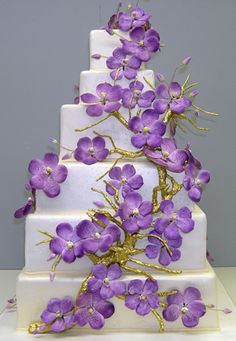 a three tiered cake with purple flowers on top