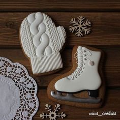 cookies decorated with ice skates and snowflakes on a wooden table next to doily