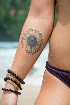 a woman's arm with a sunflower tattoo on the left side of her body