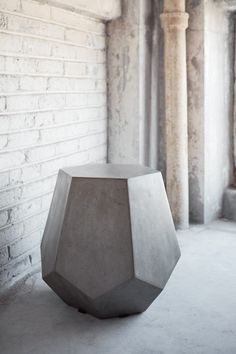 a concrete table sitting in front of a white brick wall with columns on either side