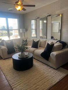 a living room filled with furniture and a large mirror on the wall above it's windows