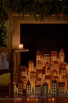 a group of lit up houses sitting on top of a table next to a window