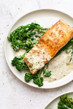 two white plates topped with fish and broccoli