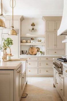 a large kitchen with white cabinets and gold lights hanging from the ceiling, along with marble counter tops