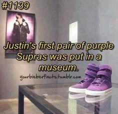 a pair of purple shoes sitting on top of a glass table next to a painting