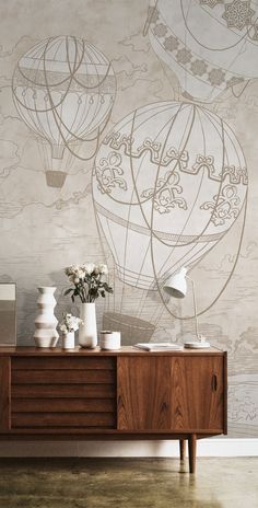 the wallpaper in this living room has hot air balloons painted on it and vases with flowers