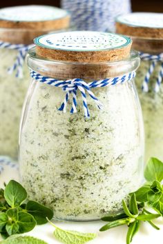 three jars filled with different types of green stuff on top of a white tablecloth