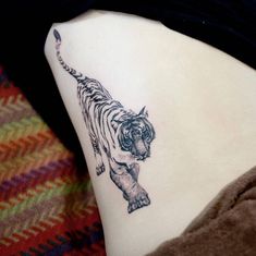 a tiger tattoo on the back of a woman's left leg, showing it's tail