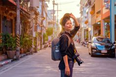 a young woman is walking down the street with her back to the camera and carrying a backpack