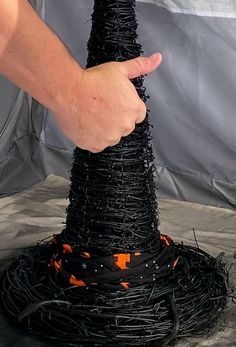 a hand is holding the top of a black wire cone with orange and white stars on it