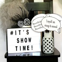 a sign that says it's show time next to a vase with feathers on it