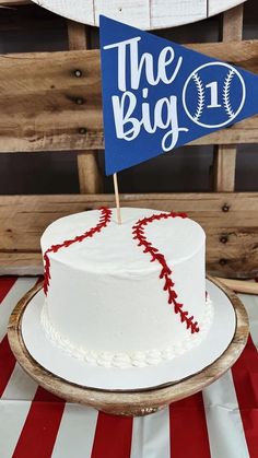 a baseball themed birthday cake with the number one on it and a flag topper