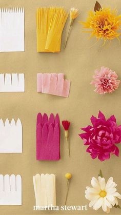 several different types of paper flowers on a brown surface with white and pink ones in the middle