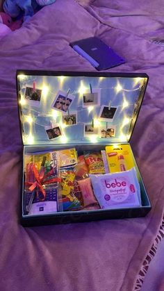 an open suitcase sitting on top of a bed covered in purple sheets and string lights