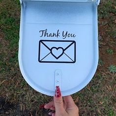 a person holding up a mailbox with a heart on it's lid that says thank you