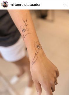 a woman's arm with a small flower tattoo on the left side of her wrist