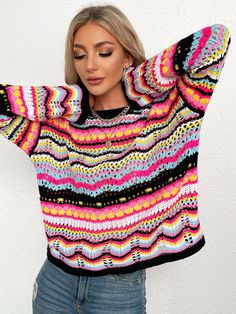 a woman wearing a multicolored sweater with her arms behind her head and looking down at the camera