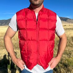 "Great puffy vest. Overall condition is good, with just some minor staining on the front right pocket (shown in pictures, but hard to see, even in person). Model normally wears a large. Measures 22\" pit to pit and 25\" long. B02" Red Sleeveless Vest Outerwear, Solid Puffer Sleeveless Vest, Casual Red Vest With Pockets, Solid Color Puffer Vest For Outdoor, Red Vest With Pockets, Red Sleeveless Vest With Pockets, Person Model, Marty Mcfly, Puffy Vest