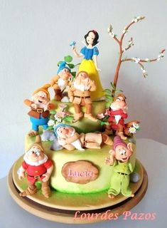 a cake with snow white and the seven dwarfs on it's tiered base