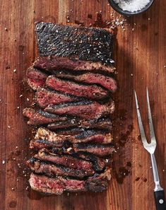 steak sliced up on a cutting board next to a knife and fork