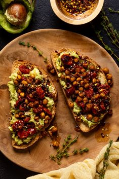 two pieces of bread on a plate topped with guacamole and chickpeas