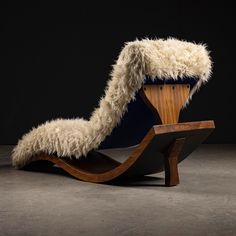 a wooden chair with fur on it and a black wall in the backround