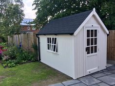 a small white shed sitting in the middle of a yard