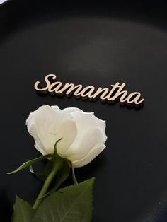 a white rose sitting on top of a black plate next to the word san antonio