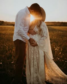 a man and woman standing in a field at sunset