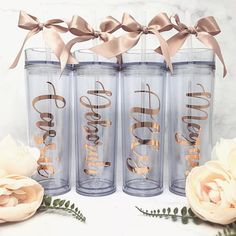 three personalized tumblers with ribbons and flowers on the table next to each other