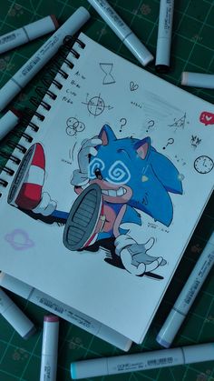 a drawing book with some markers around it and an image of a sonic the hedgehog