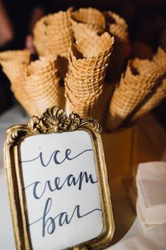 an ice cream bar sign sitting on top of a table next to waffle cones