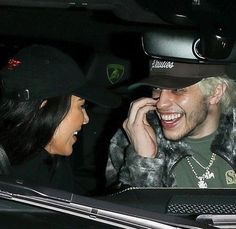 the man is talking on his cell phone as he sits in the car with another woman