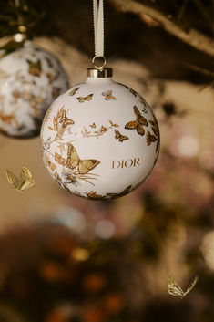 two glass ornaments hanging from a tree with butterflies on the ornament and in the background