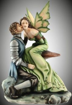 a figurine of a man and woman kissing on a rock with a green dress