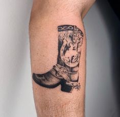 a man's arm with a tattoo of a cowboy boot and boots on it