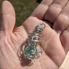 a hand holding a wire wrapped pendant in it's palm